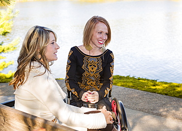 Young Paraplegic Woman And Her Friend Spending Quality Time Together In A City Park In Autumn, Edmonton, Alberta, Canada