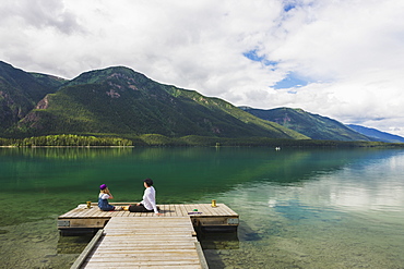 Mother And Daughter On A Dock At Muncho Lake Provincial Park, British Columbia, Canada, Summer