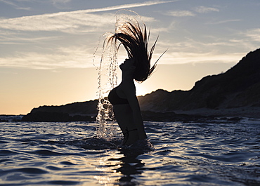 Silhouette Of A Woman In Waist-Deep Water Flipping Her Wet Long Hair Up In The Air, Tarifa, Cadiz, Andalusia, Spain