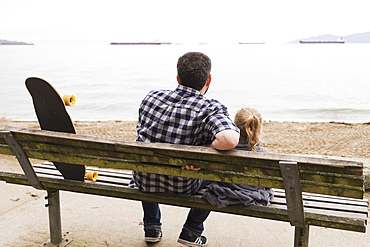 A Father And His Little Girl Sit On A Bench And Watch The Ships Anchored In The Sea, Vancouver, British Columbia, Canada