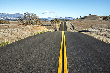 A Hilly Road With Double Solid Yellow Lines Leading Into The Distance In A Rural Area, Near Santa Ynez, California, United States Of America