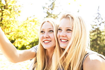 Two Sisters Having Fun In A City Park In Autumn And Talking A Selfie Of Themselves, Edmonton, Alberta, Canada