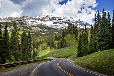 Snowcapped Rocky Mountains In The Background With A Winding Mountain Road Stretching Into The Distance, Colorado, United States Of America