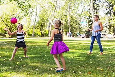 Mother And Daughters Throwing A Ball In A Park During A Family Outing, Edmonton, Alberta, Canada