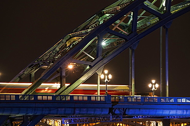 Close Up Of The Illuminated Arch Of A Bridge And Lamp Posts At Nighttime