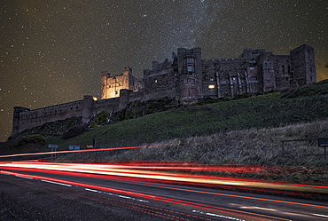 Light Trails On A Road And A Star Filled Sky Over Bamburgh Castle At Nighttime, Bamburgh, Northumberland, England