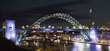 Tyne Bridge Illuminated At Nighttime Over River Tyne With A Crescent Moon In The Sky, Newcastle, Tyne And Wear, England