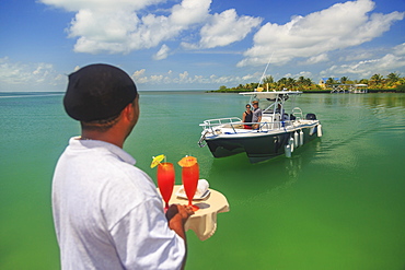 A Couple In A Boat Approaches A Dock Where A Server Is Waiting With Drinks, Saint Georges Caye Resort, Belize City, Belize