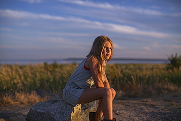 Girl In Contemplation Sitting On A Rock On The Beach At Sunset, Surrey, British Columbia, Canada