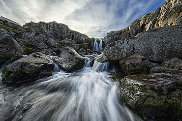 Stream Flows Over A Waterfall And Through The Rocks Along The Eastern Coast Of Iceland, Iceland