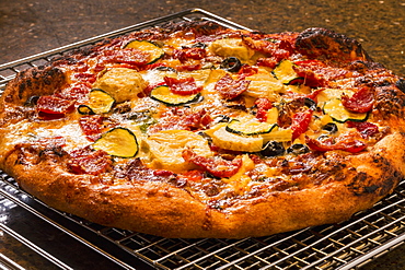 Close Up Of A Golden Crust Oven Baked Pizza On A Cooling Rack With Roasted Zucchini, Peppers, Artichokes, Mushrooms, Olives, Calgary, Alberta, Canada