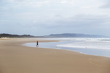 Person Walks Towards The Water On A Beach Along The Noose North Shore Under A Cloudy Sky, Noosa, Queensland, Australia