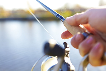 A Hand Holding A Fishing Rod And Holding It Out Over The Water, Quebec, Canada