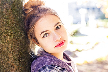 A Pretty Young Teenage Girl Looks Into The Camera With A Shy, Unconfident Look As She Leans On A Tree, New Westminster, British Columbia, Canada