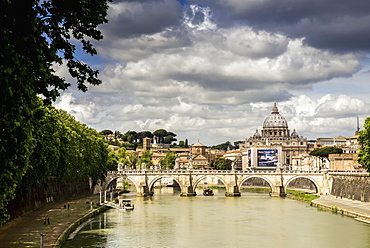 View Of St. Peter's Basilica In The Distance With A Bridge And Modern Car Advertisement Over The Tiber River, Rome, Italy