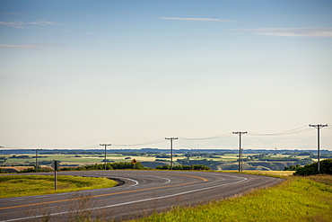 Electrical Wires Along A Curving Road With Farmland In The Distance, Saskatchewan, Canada