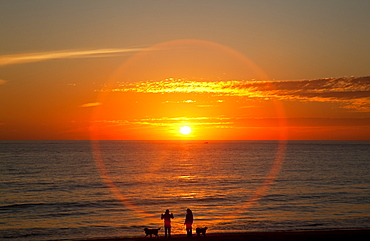 A Halo Around The Glowing Sun As It Sets Over The Ocean And An Orange Sky, Chiclana De La Frontera, Andalusia, Spain