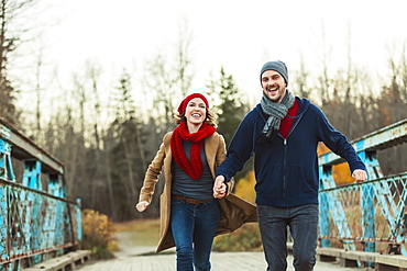 A Young Couple Running On A Bridge In A City Park In Autumn, Edmonton, Alberta, Canada