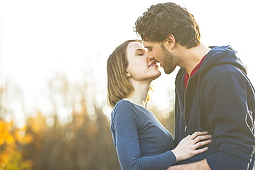 A Young Couple Holding Each Other Closely And Kissing In A City Park In Autumn, Edmonton, Alberta, Canada