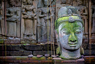 A Terra Cotta Head Of Buddha Sits In Front Of Bas-Relief In A Terra Cotta Garden, Chiang Mai, Thailand