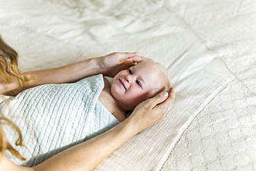 A mother's arms and hands cradle a swadled baby girl as she looks up to her mother, Sorrento, British Columbia, Canada