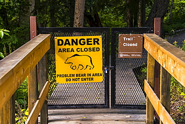 Bear warning sign posted on a closed gate where a trail has been closed, Liard River Hot Springs Provincial Park, British Columbia, Canada