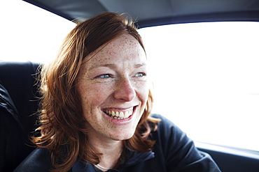 A Woman With Red Hair And Freckles Smiling While Riding In A Car, Alaska, United States Of America