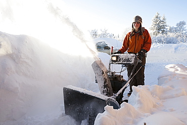 A Young Woman Uses A Snowblower In The Deep Snow, Homer, Alaska, United States Of America