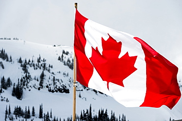 A Canadian Flag With Snow Covered Mountains And Trees In The Background, Whistler, British Columbia, Canada