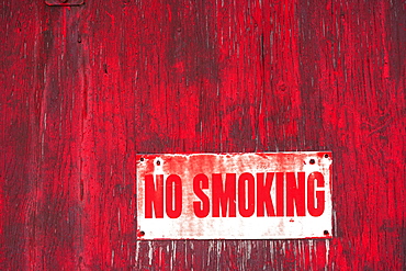 A No Smoking Sign On A Painted Red Wooden Wall, Orion, Alberta, Canada