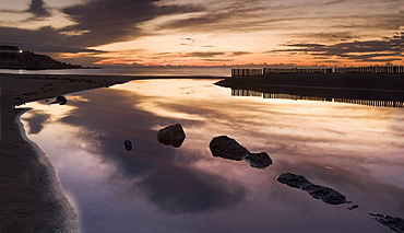 Sunset Over Water With Clouds Reflecting In Water