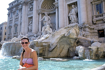 Rome, Italy; Woman Sitting On The Edge Of The Trevi Fountain