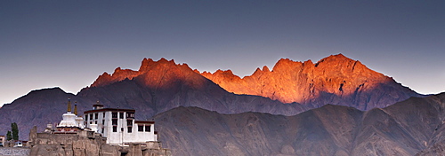 A Building On A Rock Ledge With Alpenglow Over The Mountains In The Background; Lamayuru Ladakh India