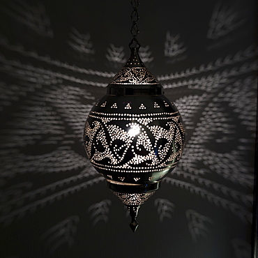 Illuminated hanging light fixture reflecting pattern on the wall, Istanbul turkey