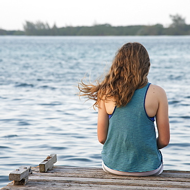 A Girl Sits On The Edge Of A Dock, Utila, Bay Islands, Honduras