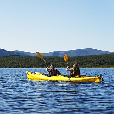 Two Young Women Kayaking In Gros Morne National Park, Trout River, Newfoundland, Canada