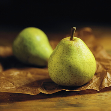 Green Pears Sitting On Brown Parchment Paper On A Wooden Counter, Toronto, Ontario, Canada