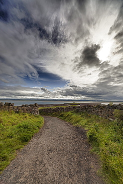 A Gravel Path Leading To The Coast Under A Cloudy Sky; Lindisfarne Northumberland England