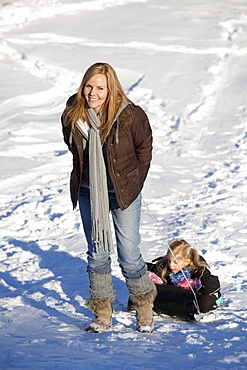 Mother Pulling Daughter Up Snowy Hill On Sled