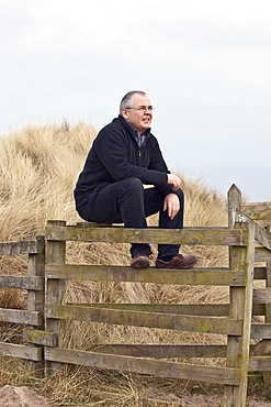 Northumberland, England, A Man Sitting On A Fence