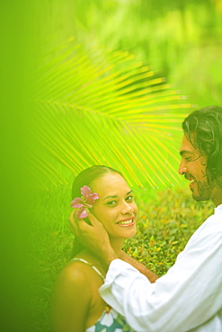 A man puts a flower in a woman's hair at the bora bora nui resort and spa, Bora bora island society islands french polynesia south pacific