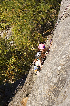 Young Woman Climbing With Daughter (Age 7) Up Granite Cliff At Stone Hills Near Rexford, Montana, Usa