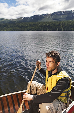 Man In Canoe On Byers Lake With Forested Foothills In The Background, Byers Lake Campground, Denali State Park, Alaska, United States Of America