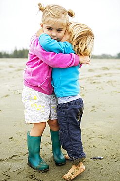 Young Girl And Boy Have A Warm Hug And Cuddle On The Beach In Summer, Tofino, British Columbia, Canada