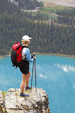 Female Hiker On Rock Cliff Overlooking Blue Alpine Lake, British Columbia, Canada