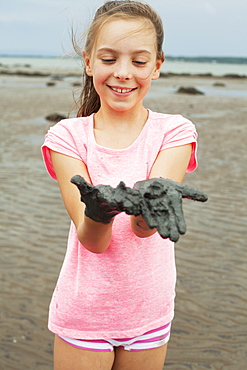 Young Girl Wearing Pink On A Shore Showing Her Muddy Hands, Charlevoix, Quebec, Canada