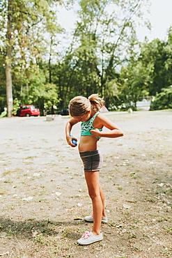 A Young Girl Applies Sunscreen On Her Skin, Peachland, British Columbia, Canada