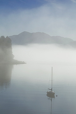 Low Fog And Mist Burn Off Along The Shoreline In Alaska's Inside Passage Where A Sailboat Rests At Anchor In A Small Cove Near Juneau, Alaska. Tongass National Forest.