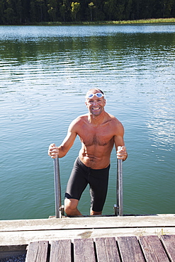 Man Getting Out Of The Water Onto A Dock, Morbylanga, Sweden