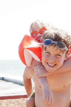 Young Brothers Play On The Sand Beach With Water And Dock In The Background, Alberta, Canada